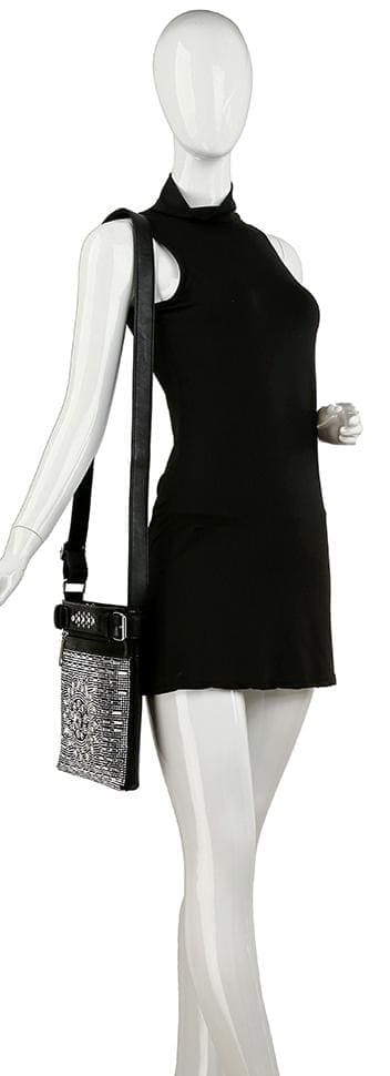 A mannequin in a sleeveless black mini dress with a high neckline carries the Brilliant Rhinestone Crossbody Sling, a black faux leather bag featuring a sparkly silver front panel and adjustable strap.