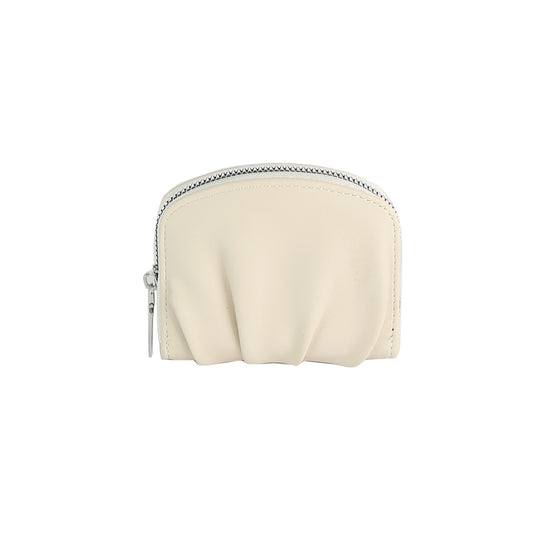 The Petite Pleated Zip Around Wallet is a small, cream-colored faux leather pouch with a curved top, ruched detailing on the front, and a secure zip closure, shown against a plain white background.