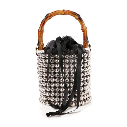 The Beaded Unique Evening Bag is a petite bucket bag with a bamboo handle, shiny silver beads, a stylish beaded silhouette, black drawstring closure, and long black ribbon ties.