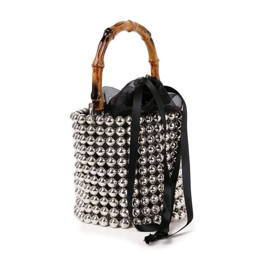 The Beaded Unique Evening Bag is a petite bucket bag with shiny silver beads, a bamboo handle, black drawstring closure, and a stylish black ribbon accent.