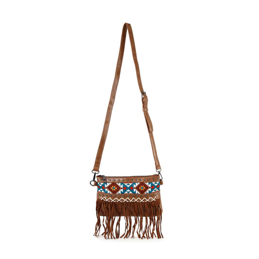 The Southwest Patterned Shoulder Bag features brown faux leather, an adjustable strap, colorful Aztec geometric embroidery, and fringe along the bottom, displayed against a white background.