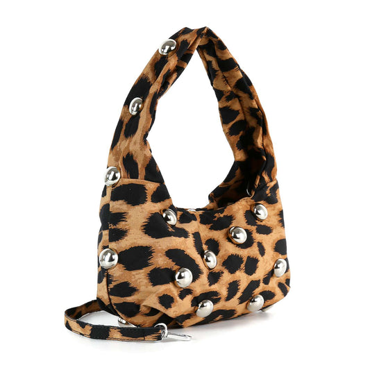 The Leopard Print Studded Petite Hobo is a small hobo bag with bold brown and black leopard print, large silver studs, a short handle, and a detachable strap for versatile styling.