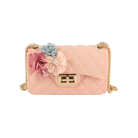 The Floral Accented Petite Jelly Shoulder Bag is a quilted light pink handbag with a single strap, gold tone hardware, a twist lock closure, and pastel floral appliqués in pink, peach, and light blue on the top left corner.