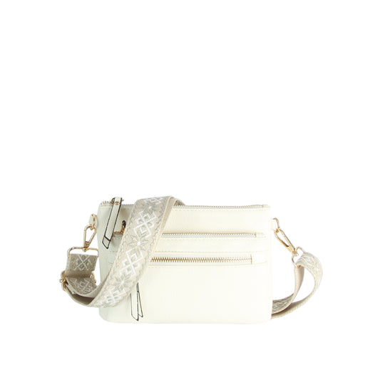 The Guitar Strap Crossbody Sling Handbag is a small white faux leather bag with dual zip pockets, a detachable geometric-patterned beige and white strap, and gold-tone hardware.