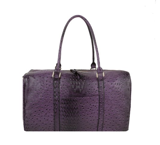 The Classic Embossed Carry-On Satchel is a purple, textured faux leather bag with two handles, a rectangular shape, crocodile or ostrich skin pattern, and a front pocket—ideal as a stylish travel tote, shown on a white background.