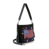 The Americana Flag Burst Hobo Crossbody is a black faux leather bag with a beaded American flag and fireworks design, featuring a tassel zipper pull and detachable crossbody strap.
