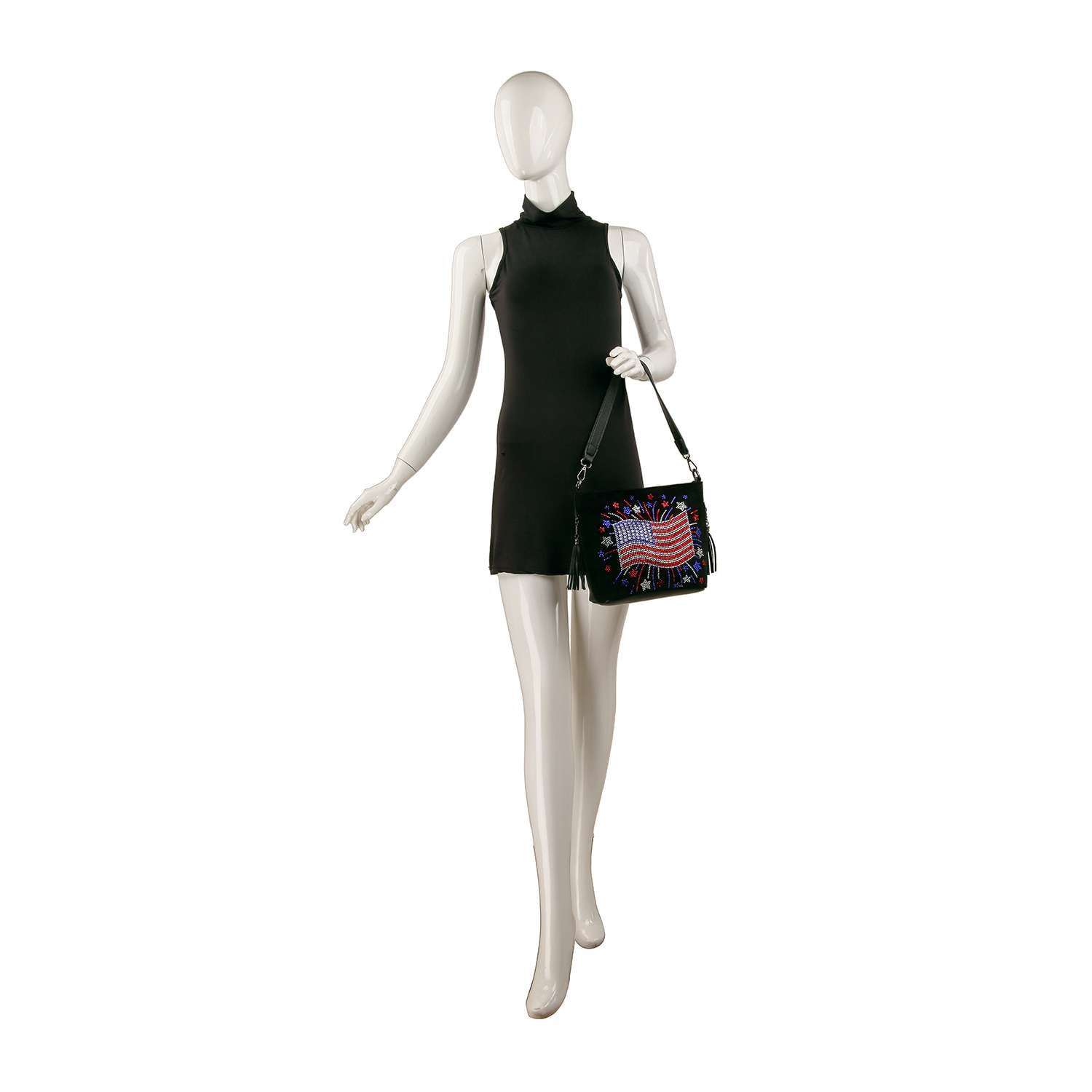 A mannequin in a sleeveless black mini dress holds the Americana Flag Burst Hobo Crossbody, a faux leather bag with a colorful American flag motif. The background is plain white.