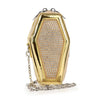 The Rhinestone Coffin Style Petite Patent Shoulder Bag is a gold coffin-shaped bag embellished with sparkling rhinestones and features a metallic chain strap draped in front for gothic flair.