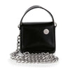 The Chain Accented Evening Bag is a small black faux leather micro evening bag featuring a top handle, front flap with silver button, and detachable long silver chain strap.