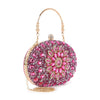 The Highly Decorative Retro Evening Bag is an oval-shaped evening bag with pink and gold gemstones in a floral pattern, a gold handle, side chain handle, decorative clasp, and luxe faux leather for an elegant touch.