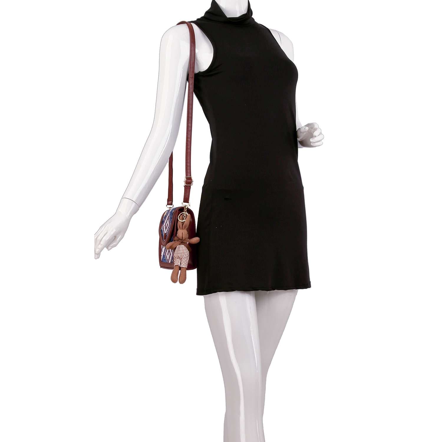 A mannequin wears a sleeveless black turtleneck dress with the Decorative Accent Shoulder Bag, a lightweight brown crossbody featuring an adjustable strap and a teddy bear-shaped keychain.