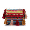 The Tassel Accented Woven Design Shoulder Bag features diamond patterns in blue, green, pink, and yellow, plus red, gold, and tan tassels with a braided trim on the flap for a vibrant boho look.