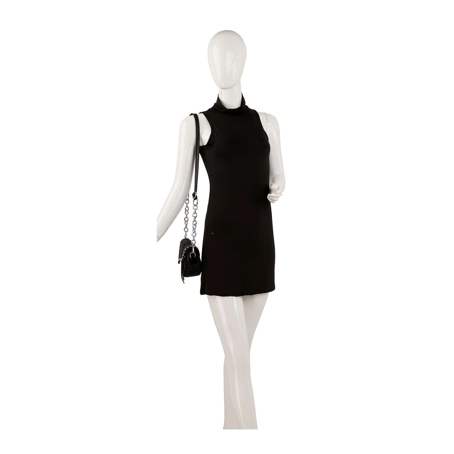 A mannequin wearing a sleeveless, high-neck black mini dress and carrying the Chain Handle Petite Shoulder Bag in black faux leather.