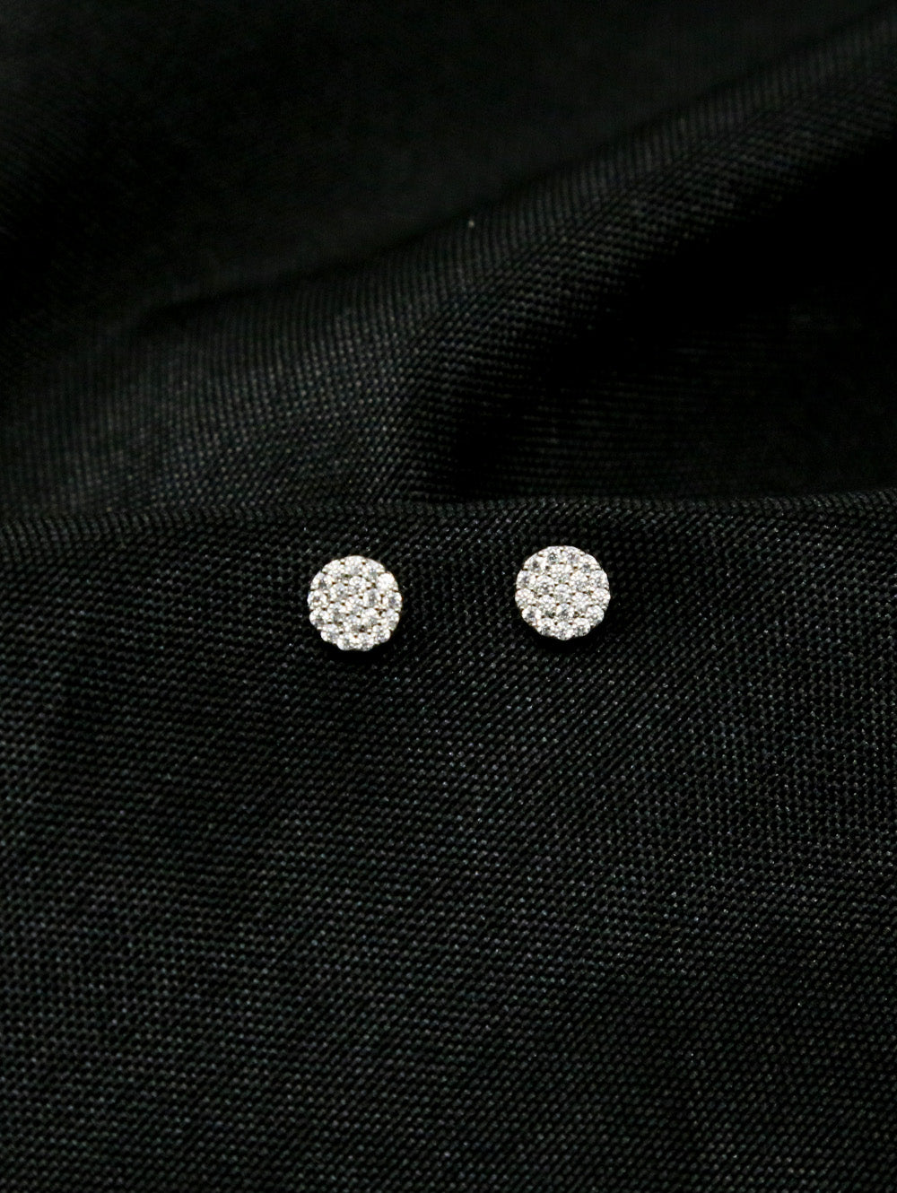 Fashion Rhinestone Earrings, round and silver with sparkling rhinestones, are displayed on a textured black fabric background.