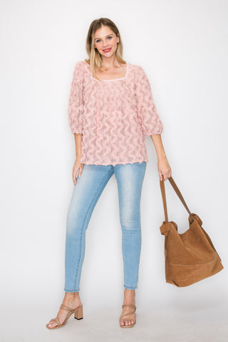 A woman stands against a white background in a textured pink top, light blue jeans, and tan heeled sandals, smiling with one hand on her hip. She carries the Genuine Leather Two-In-One Hobo Handbag Set, perfect for everyday use.