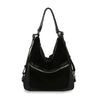 The Genuine Leather Convertible Hobo Backpack, in black with silver zippers and adjustable shoulder straps, is crafted from genuine leather and displayed upright against a white background.