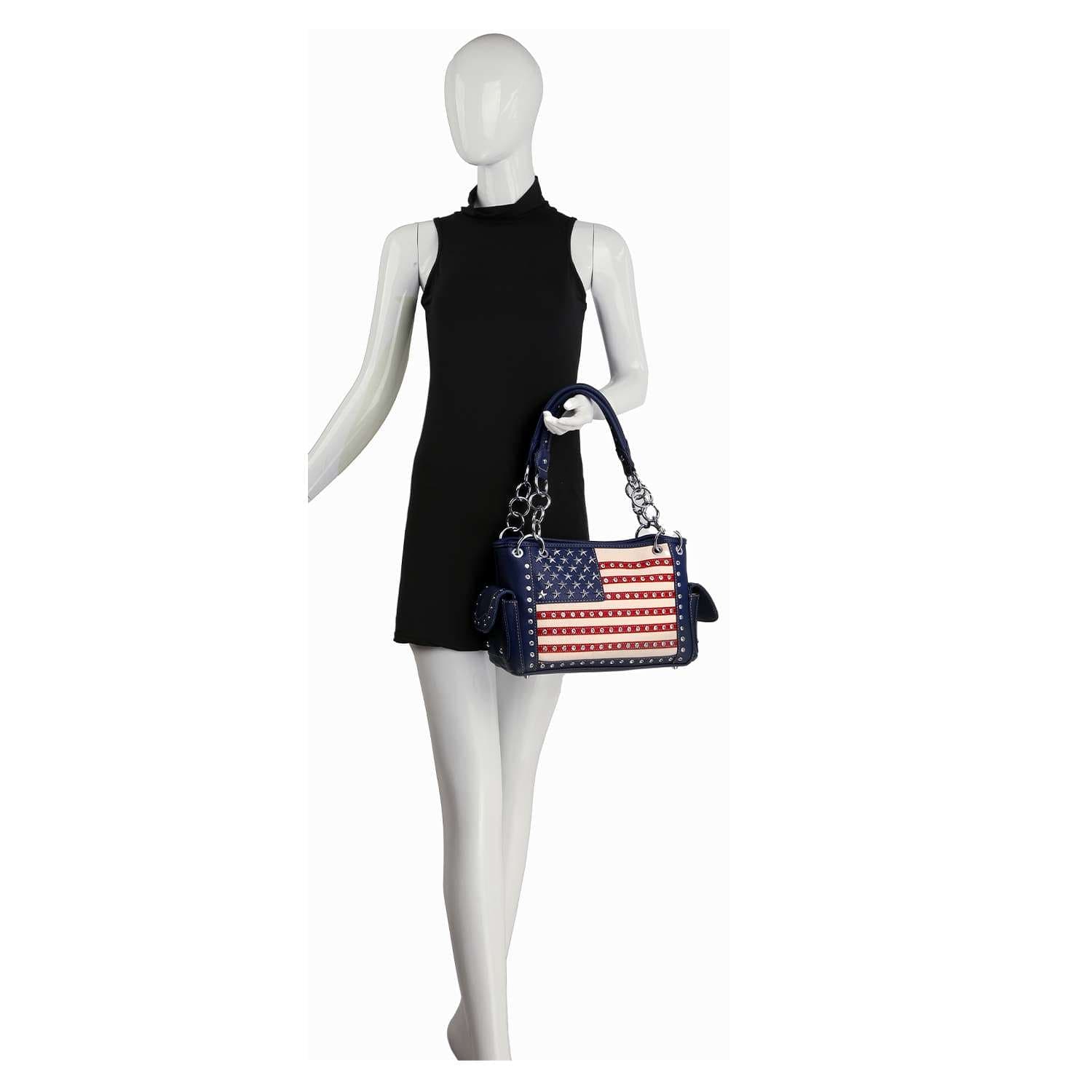 A mannequin in a sleeveless black dress holds the American Flag Rhinestone Handbag, a faux leather purse styled as a USA flag shoulder bag with red, white, blue colors, stars, and stripes.
