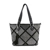The Diamond Pattern Shopper Style Tote features black faux leather, two shoulder straps, a geometric diamond pattern with white studs, and a black tassel keychain. Tablet compatible, it combines style with everyday functionality.
