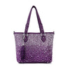 The Glamorous Rhinestone Shopper Tote is a purple faux leather handbag with two handles, silver studs in a scattered pattern, and a matching tassel accessory hanging from one handle.