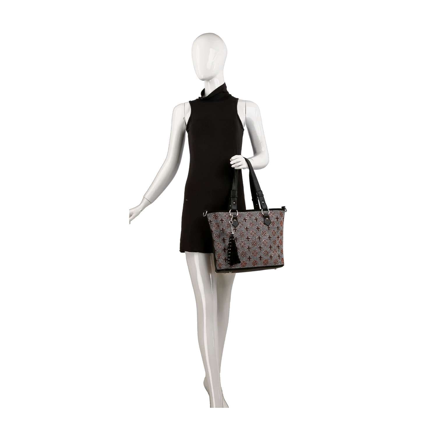 A mannequin in a sleeveless black dress holds the Rhinestone Signature Print Classic Tote Bag with black handles and a black tassel, displayed against a plain white background.