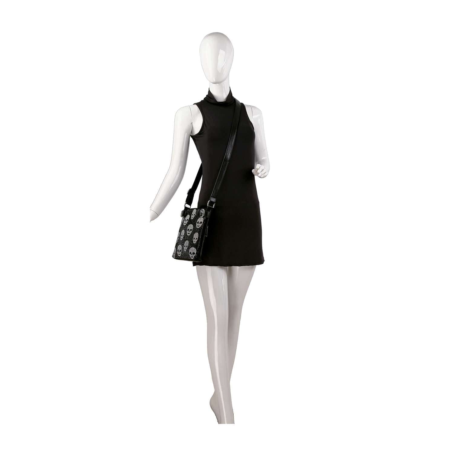A mannequin in a sleeveless black mini dress poses with the Rhinestone Skull Pattern Crossbody Sling, featuring white rhinestone skull designs, set against a plain white background.