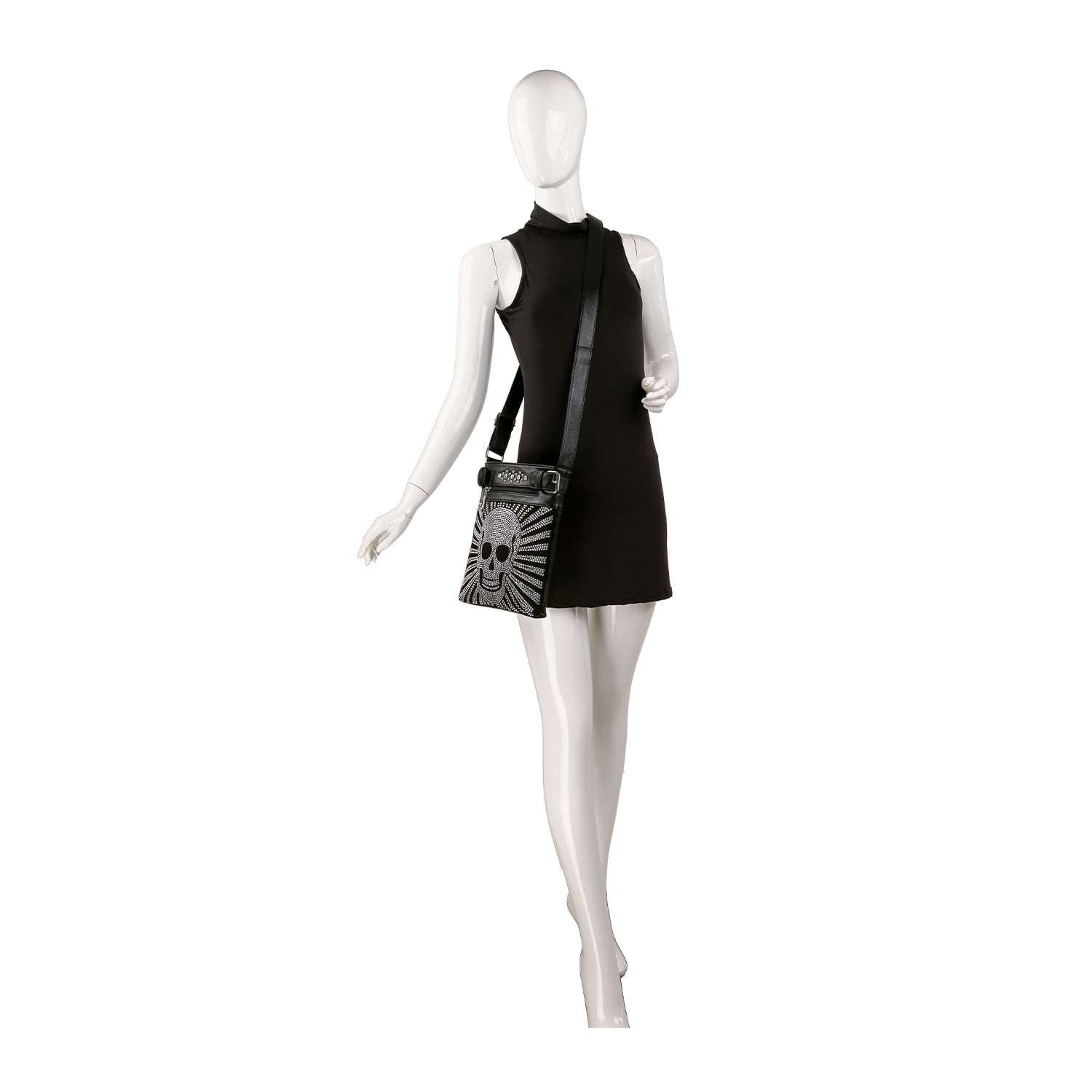 A mannequin in a sleeveless black mini dress showcases the Dazzling Skull Design Crossbody Sling, a faux leather bag with a striking skull and sunburst motif. The mannequin poses on one leg, with one arm bent and the other outstretched.
