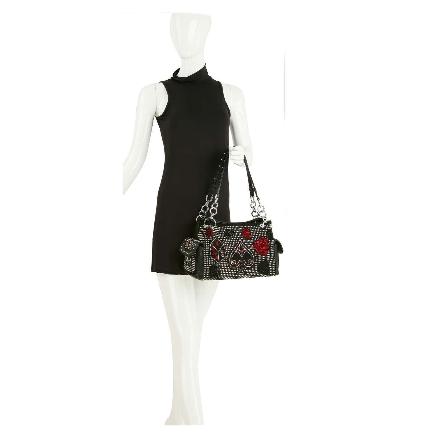 A mannequin in a sleeveless black dress displays the Playing Card Emblems Design Rhinestone Handbag, featuring decorative playing card suit symbols and red accents, held over its shoulder.