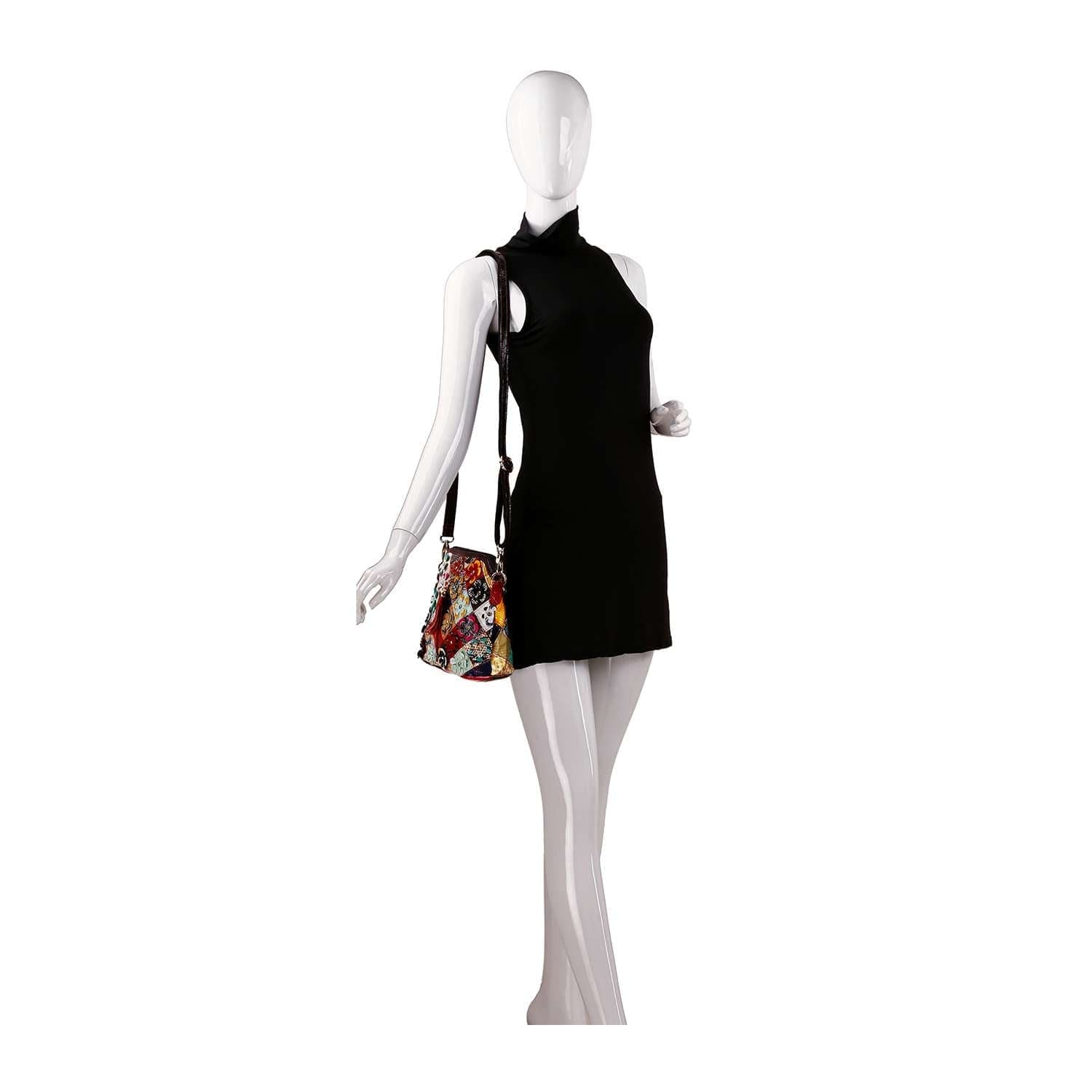 A mannequin in a sleeveless black mini dress holds the Genuine Leather Multi Color Floral Shoulder Bag with gold hardware over one shoulder, posed against a plain white background.
