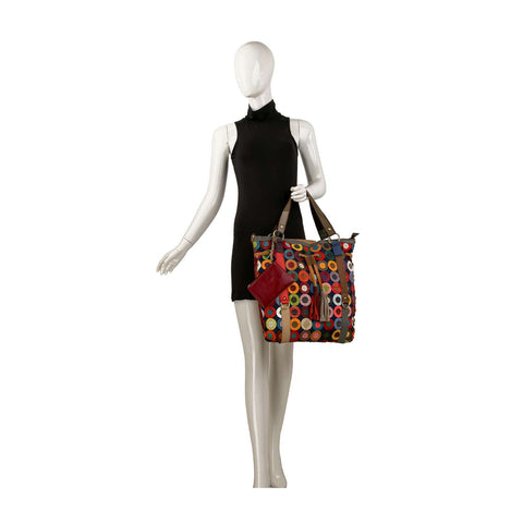 A mannequin in a sleeveless black dress holds the Genuine Leather Oversized Tote Handbag featuring a colorful circular pattern and a matching red pouch. The plain white background highlights this statement accessory.