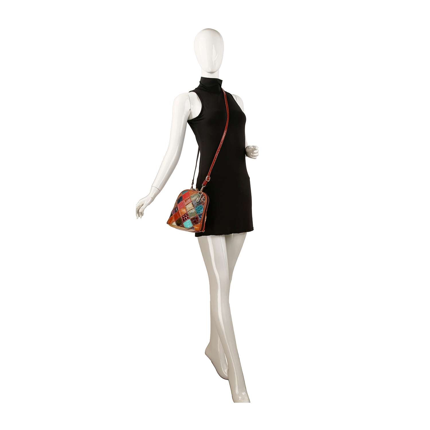 A mannequin in a sleeveless black mini dress showcases the Genuine Leather Patchwork Crossbody Sling, featuring a colorful pattern, adjustable strap, and gold-toned hardware against a white background.