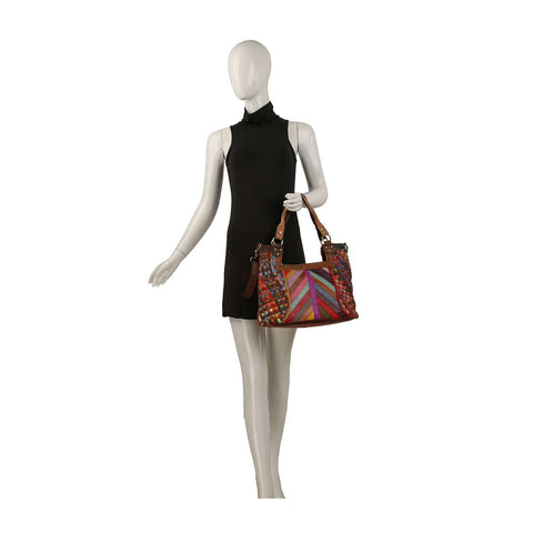 A mannequin in a sleeveless black dress holds the Genuine Leather Colorful Woven Shoulder Bag, featuring geometric and dot patterns, gold-toned hardware, and brown handles and accents against a plain white background.