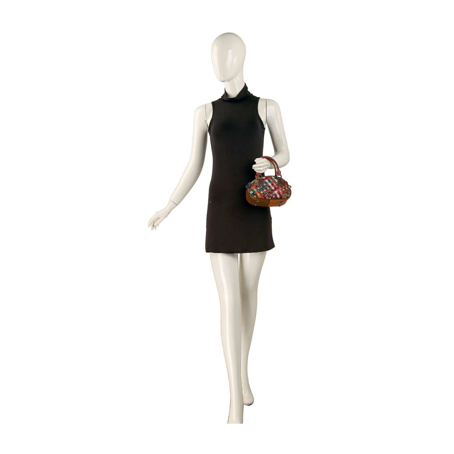 A mannequin in a sleeveless black mini dress holds the Genuine Leather Woven Petite Hand Tote in its left hand, set against a plain white background.
