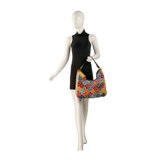 A mannequin in a sleeveless black dress holds the Genuine Leather Raised Flower Shoulder Bag, featuring handcrafted colorful patchwork, against a plain white background.