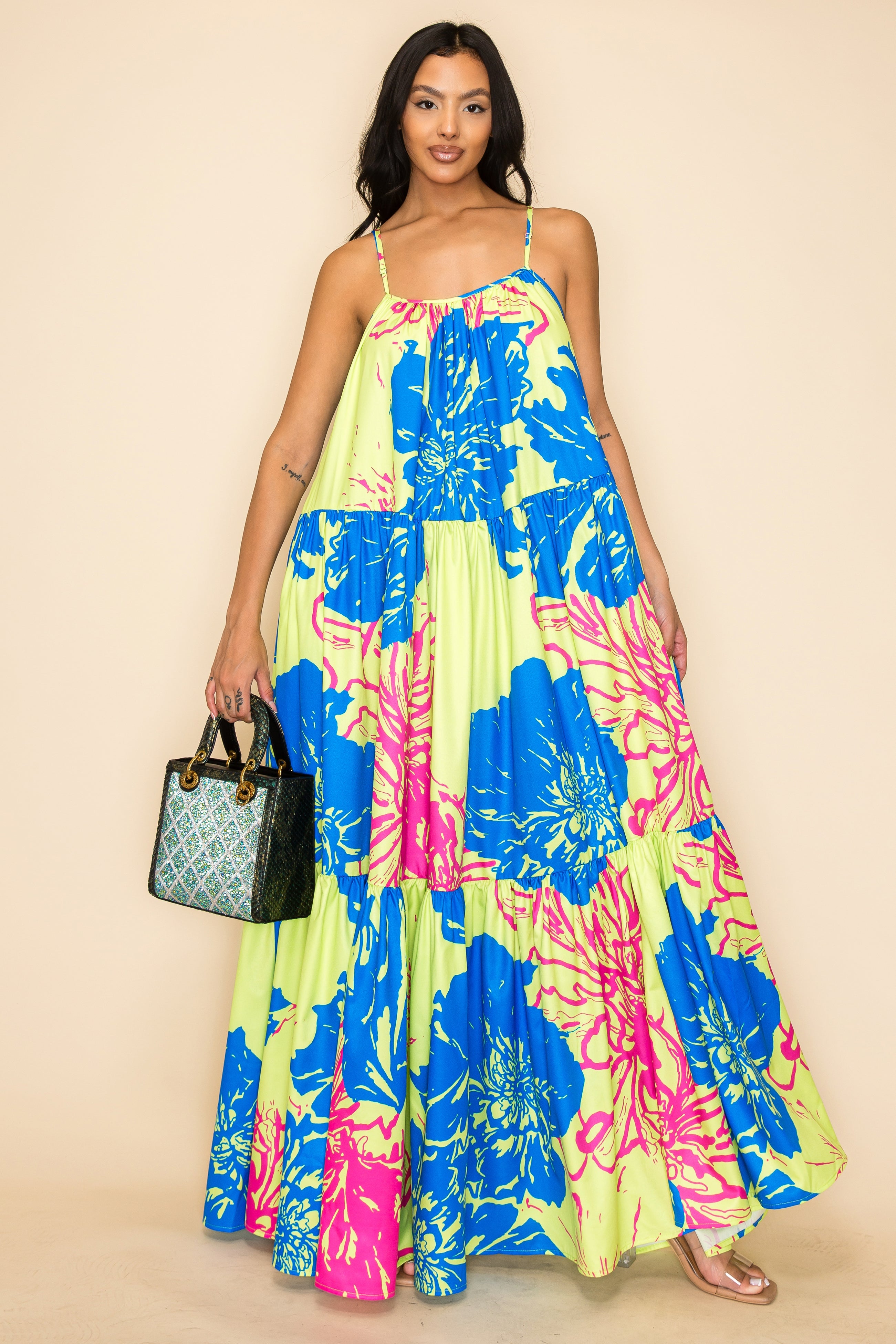 A woman stands against a beige background in a flowy floral maxi dress, carrying the Colored Stone Grid Pattern Tote Handbag and wearing clear open-toe sandals.