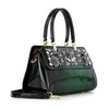 The Sparkling Patent Decorative Hand Tote is a glossy dark green faux leather bag with black handles, a detachable shoulder strap, silver floral embellishments, and decorative stones on the upper front panel.