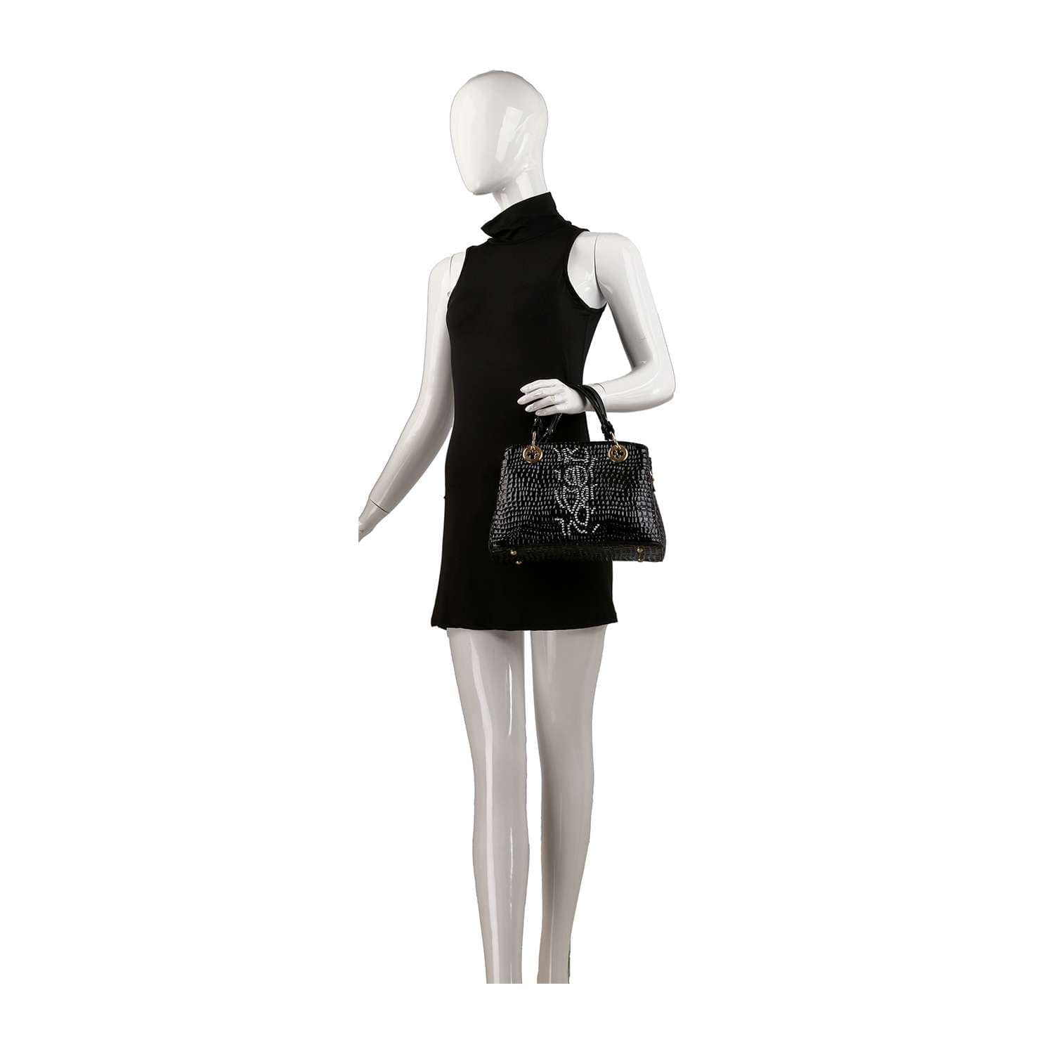 A mannequin in a sleeveless black dress holds the Snake Embossed Hand Tote Set, featuring a black faux leather tote with short handles and gold hardware, displayed against a plain white background.