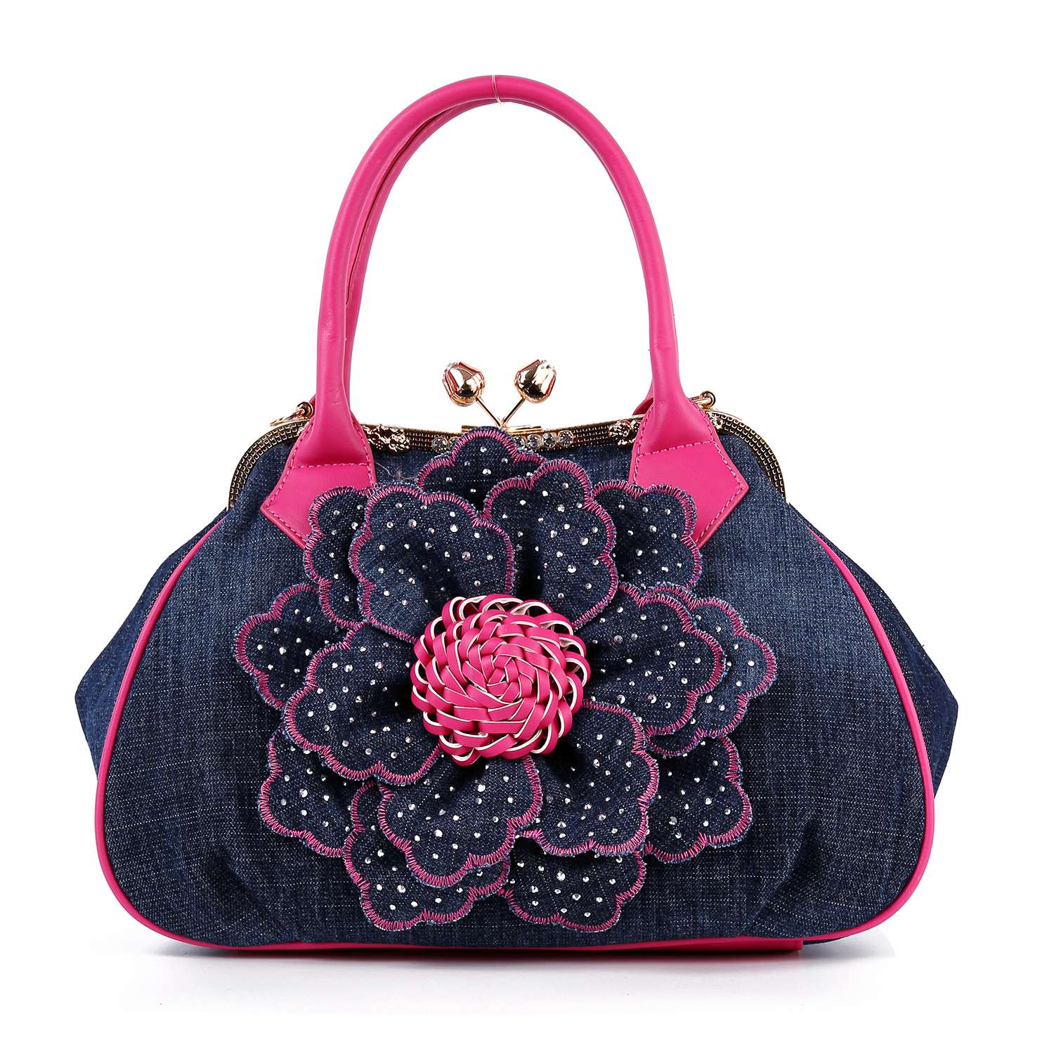 The Raised Flower Metal Frame Hand Tote is a vintage-chic denim bag with bright pink handles and a large decorative denim flower adorned with silver studs and a pink woven center on the front.