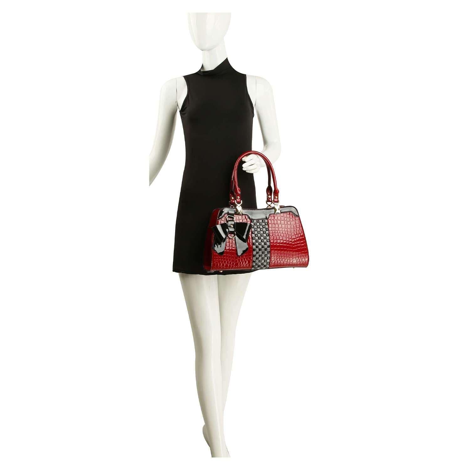 A mannequin in a sleeveless black dress holds the Brilliant Bow Sparkling Hand Tote, featuring embossed croc texture, gold hardware, and a decorative bow.
