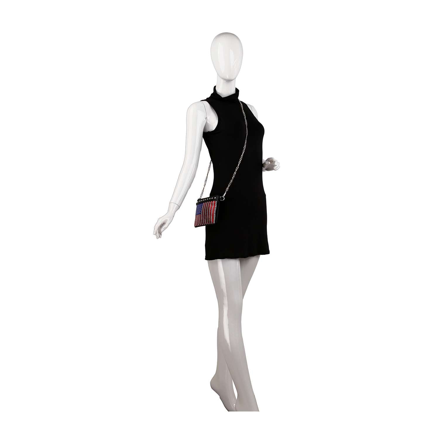A white mannequin models a sleeveless black mini dress with the Rhinestone Flag Crossbody Sling, featuring a small faux leather design and chain strap, posed against a plain white background.