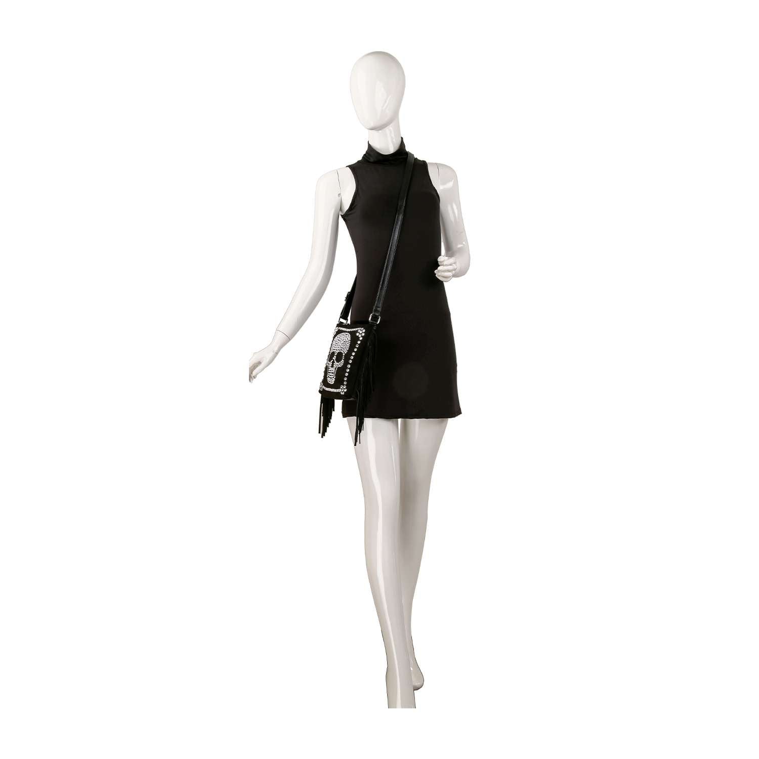 A white mannequin wears a sleeveless short black dress and holds the Skull Accented Fringe Shoulder Bag, featuring chic white decorative patterns, posed against a plain white background.