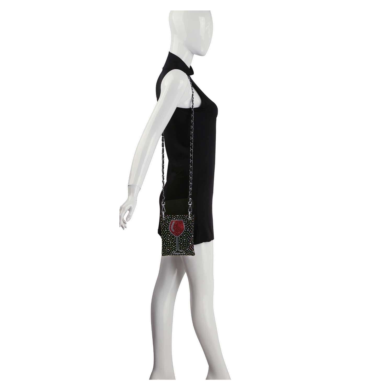 A mannequin poses against a white background wearing a sleeveless black mini dress and carrying the Red Wine Glass Petite Crossbody Sling, a small faux leather handbag with a chain strap and red detail.