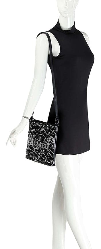A mannequin in a sleeveless black dress showcases the Blessed Rhinestone Crossbody Sling, featuring faux leather, silver studs, and Blessed spelled out in sparkling rhinestones.