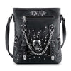 The Stud and Chain Accented Skull Crossbody Sling features black faux leather, silver studs, buckle accents, chain details, a bold metallic skull on the front, zippered pocket, and an adjustable strap.