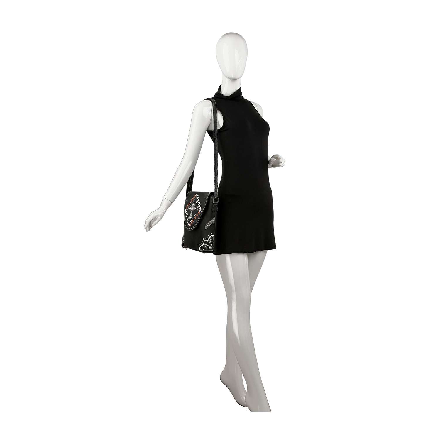 A white mannequin in a sleeveless black dress poses with the Decorative Cross Accented Top Flap Crossbody Sling, adorned with colorful patches and designs.