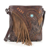 The Western Fringe Design Crossbody Sling features tooled floral patterns, tan suede fringe, decorative studs, and a turquoise stone accent. Made of faux leather, it has an adjustable strap and classic western-style details.