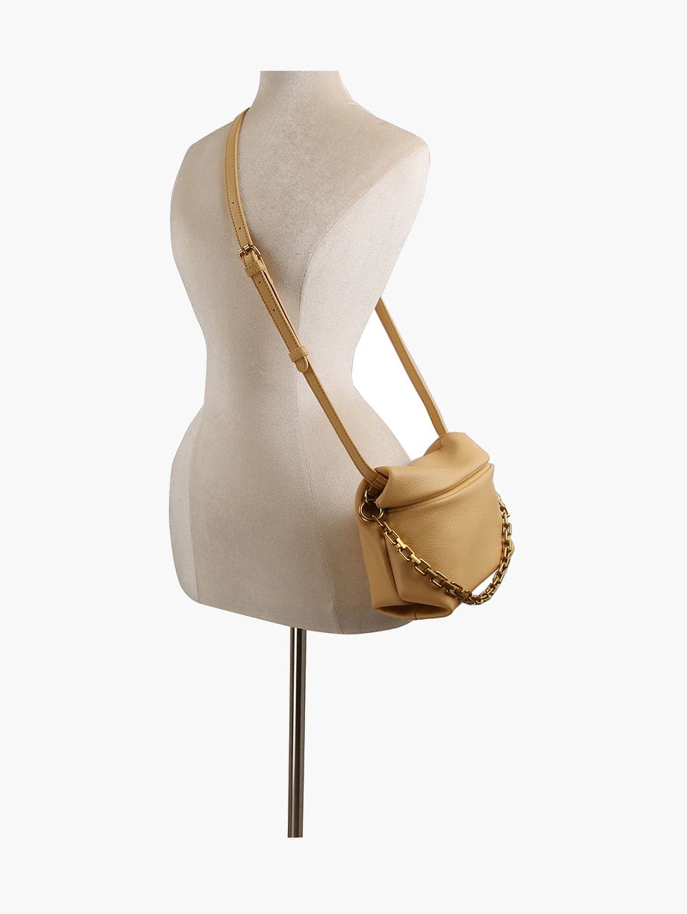 The Chain Accented Front Flap Shoulder Bag, made from beige faux leather with gold chain and hardware accents, is shown on a dress form mannequin against a white background.