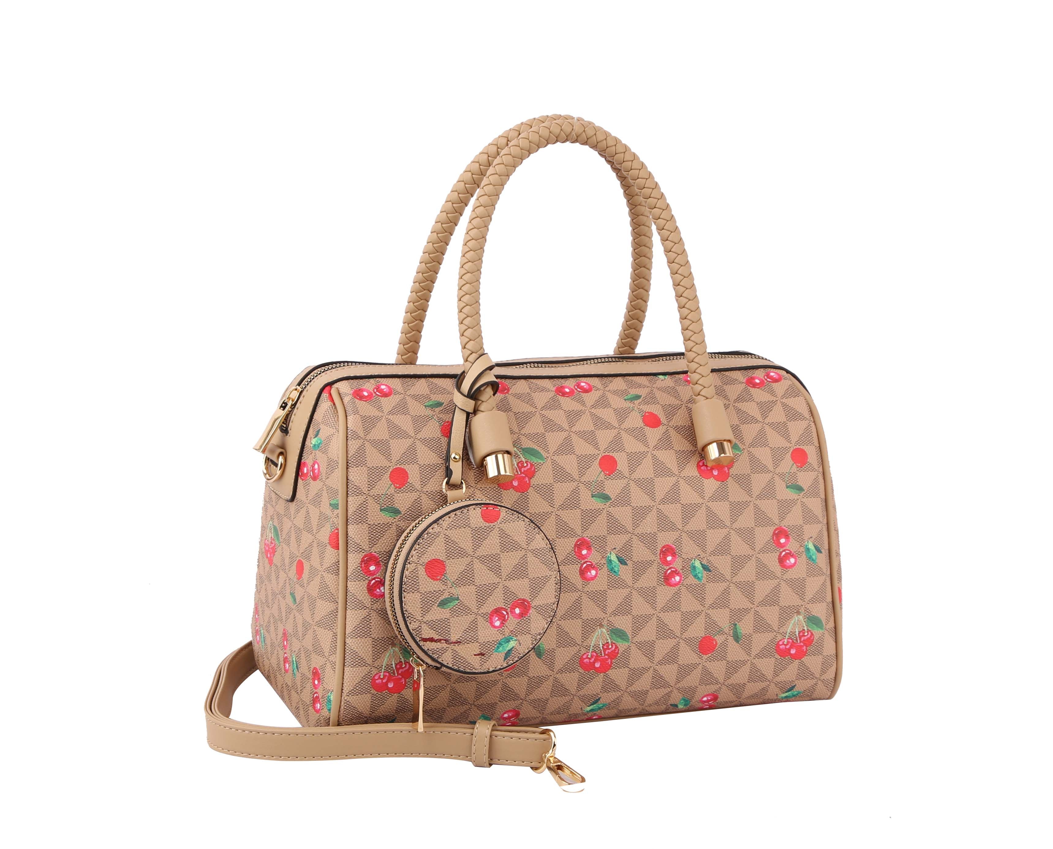 The Signature Cherry Print Satchel Set is a beige faux leather bag with braided handles, a detachable strap, and a geometric cherry pattern. It comes with a round coin pouch attached to one handle and features gold hardware for added style.