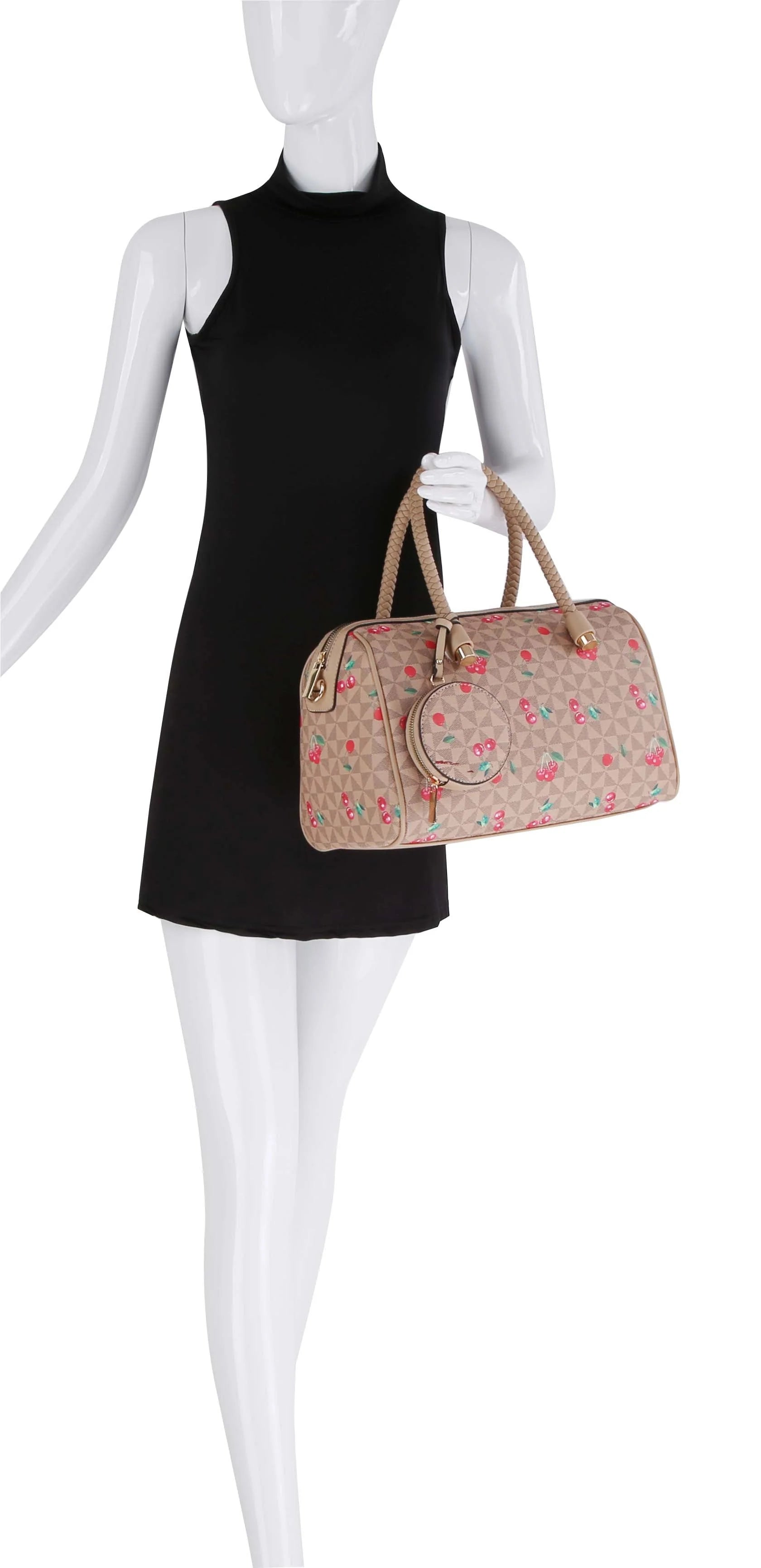 A mannequin in a sleeveless black dress holds the Signature Cherry Print Satchel Set, a beige faux leather handbag with a pink cherry pattern, tan handles, and a detachable strap.