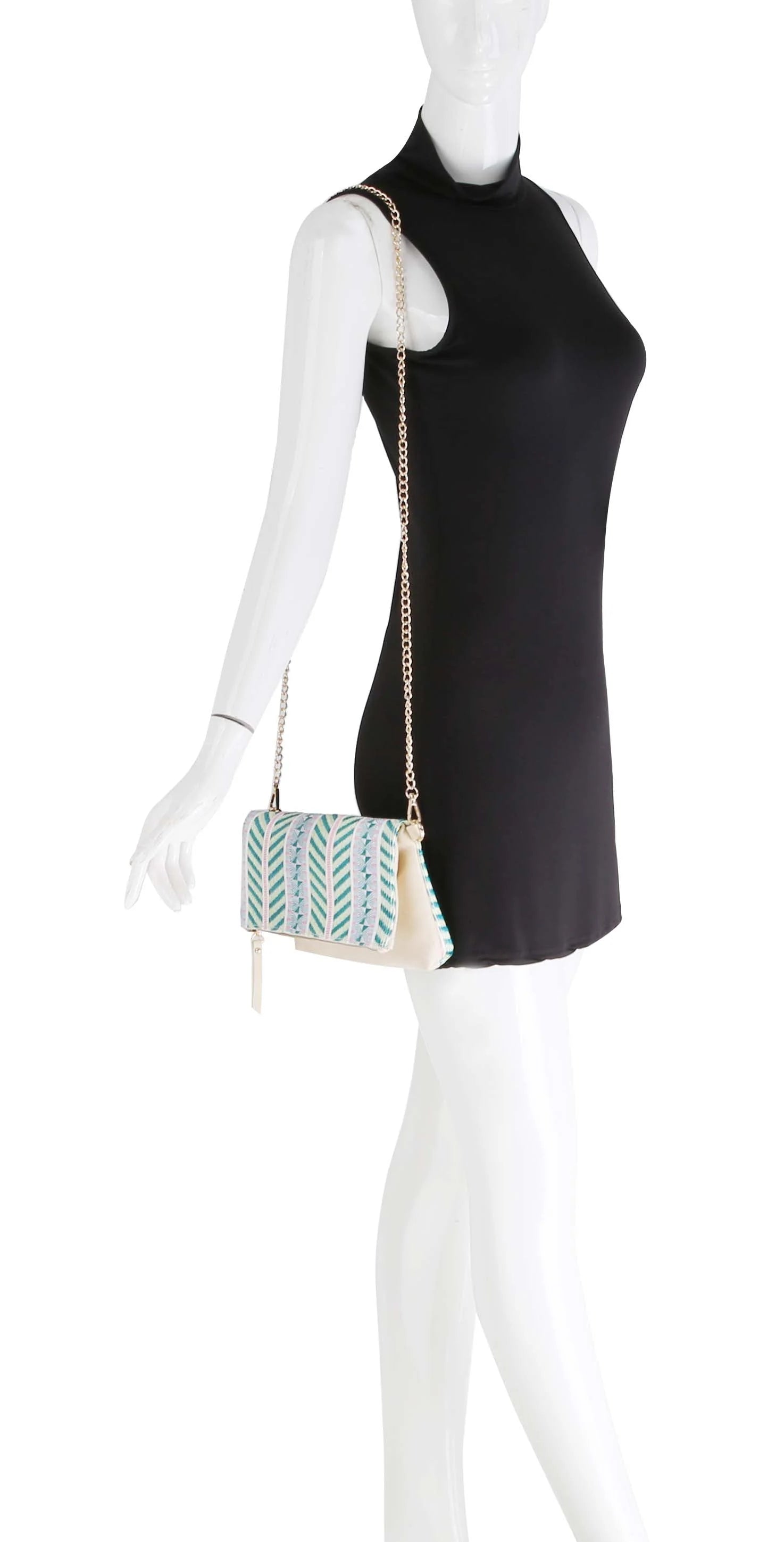 A mannequin in a sleeveless black dress displays the Colorful Woven Crossbody Bag with a gold chain strap, gold toned hardware, and a white faux leather body embellished with green and blue embroidered patterns.