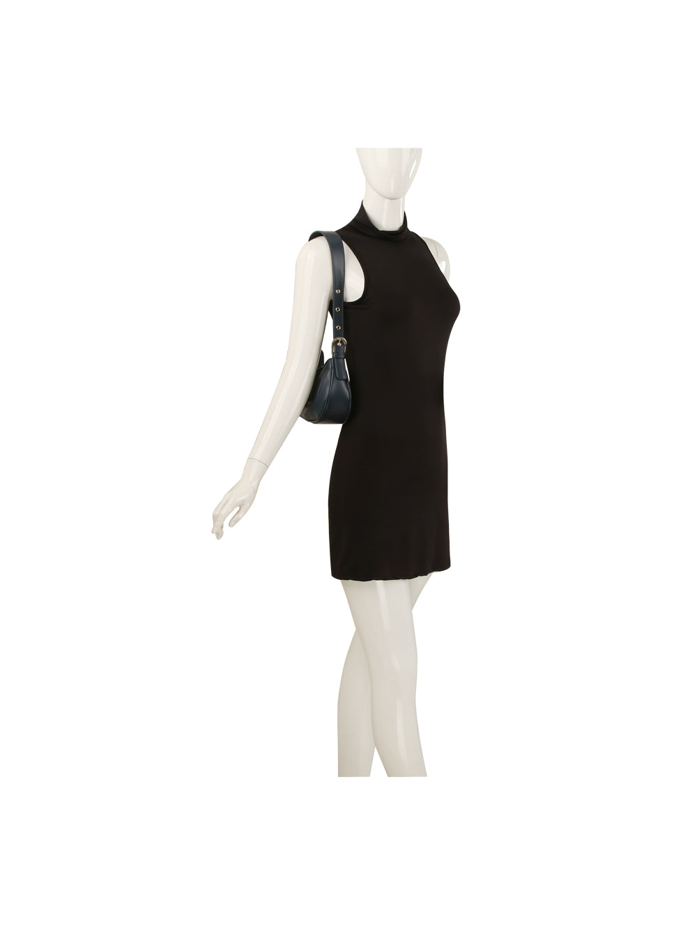A white mannequin wears a sleeveless black mini dress and carries the Buckle Accented Petite Shoulder Bag, a small black shoulder bag with gold-toned hardware. The mannequin is posed with one arm slightly extended.